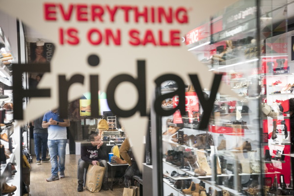 This photo shows a store selling shoes as viewed from outside one of the shop's windows. The window has the words "EVERYTHING IS ON SALE Friday" on it.