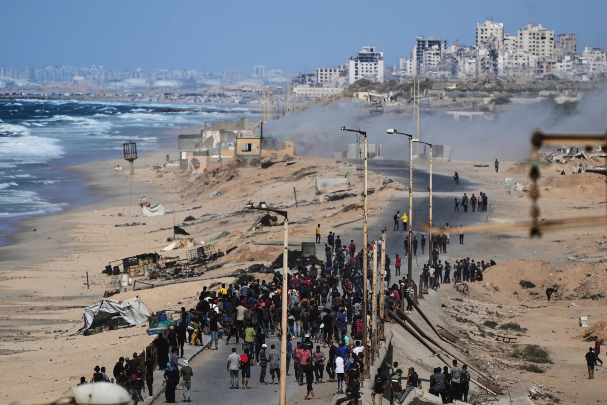 Displaced Palestinians gather on the coastal road near Wadi Gaza after the announcement that Israel and Hamas had agreed to the first phase of a peace plan to pause the fighting, as Israeli tanks block the road leading to Gaza City, in the central Gaza Strip, Thursday, Oct. 9, 2025.