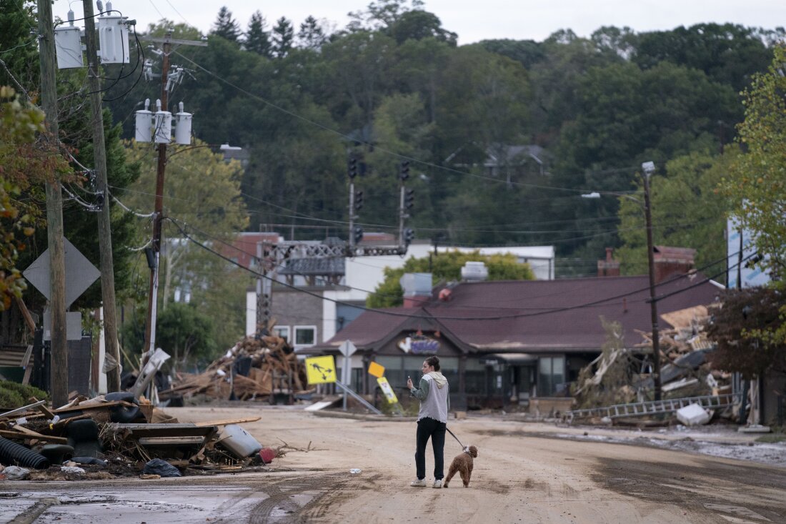 A woman and her dog walk around Asheville after the storm.
