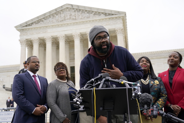 Evan Milligan (center) speaks outside the U.S. Supreme Court in Washington, D.C., in 2022 after the justices heard oral arguments in the voting rights lawsuit he and other Black voters filed over Alabama’s congressional voting map.
