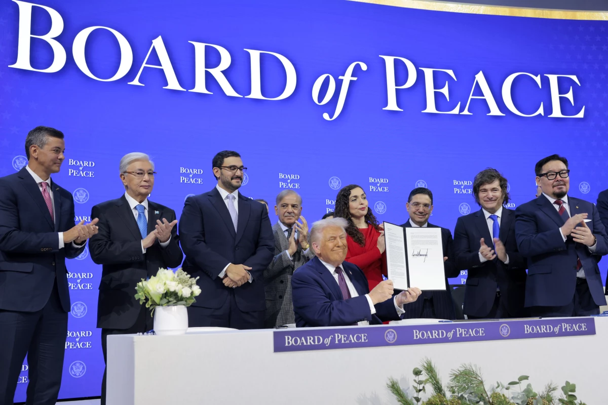 President Trump holds up his signature on the founding charter during a signing ceremony for the Board of Peace at the World Economic Forum on Thursday in Davos, Switzerland. The final makeup of the board has not been confirmed.