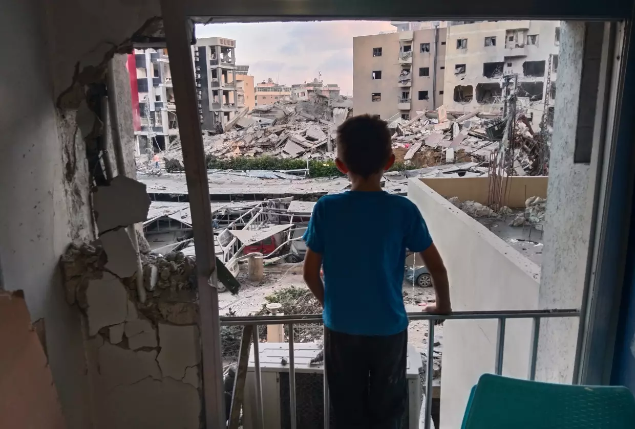 A boy looks through a damaged room of the Jabal Amel Hospital into a destroyed building that was hit in an Israeli airstrike in the southern port city of Tyre, Lebanon, June 1, 2026.