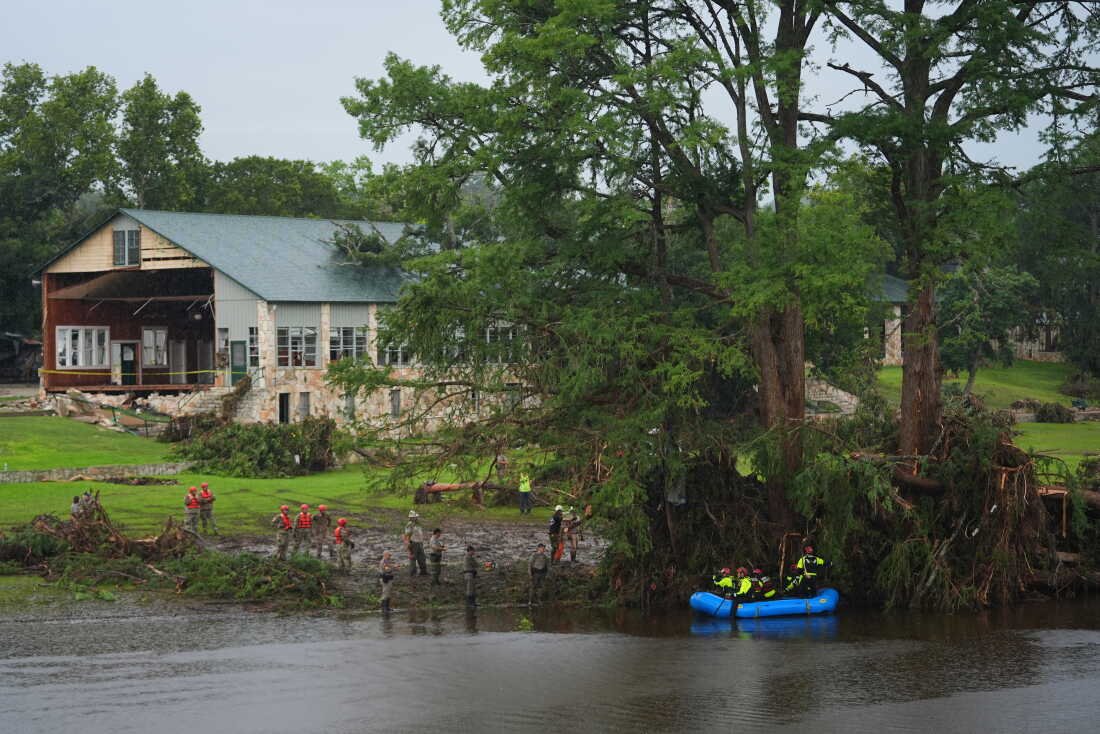 Rescue workers are seen on land and on a boat as they search for missing people near Camp Mystic in Hunt, Texas, along the Guadalupe River after a deadly flash flood swept through the area in July 2025.