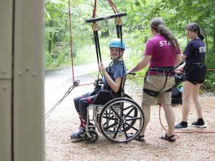 Lucas Hardy, 14, uses a hoist to climb the rock wall at Camp Cranium.