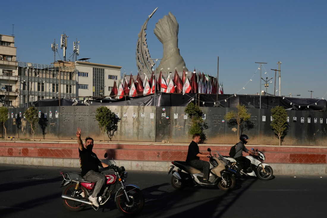 A man reacts to the camera while driving past a monument depicting the clenched fist of the late Iranian Supreme Leader Ayatollah Ali Khamenei, who was killed in U.S. and Israeli strikes on Feb. 28, and a missile at the Islamic Revolution square in downtown Tehran, Iran, Tuesday.