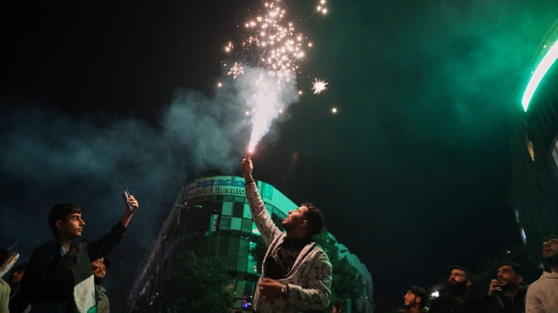 A man lights a flare during celebrations marking the first anniversary of the ousting of the Bashar al-Assad regime in Clock Square, Homs, western Syria, Monday.