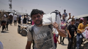 Omar al-Hobi, 43, from Rafah, carries a bag of food he collected at a distribution center run by private contractor the Gaza Humanitarian Foundation in the southern Gaza Strip, as he arrives at his tent in Khan Younis, on June 10.