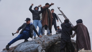 Residents topple a statue of a female Kurdish fighter after the takeover of the town by Syrian government forces from U.S.-backed Syrian Democratic Forces (SDF), in Tabqa, eastern Syria, on Sunday.
