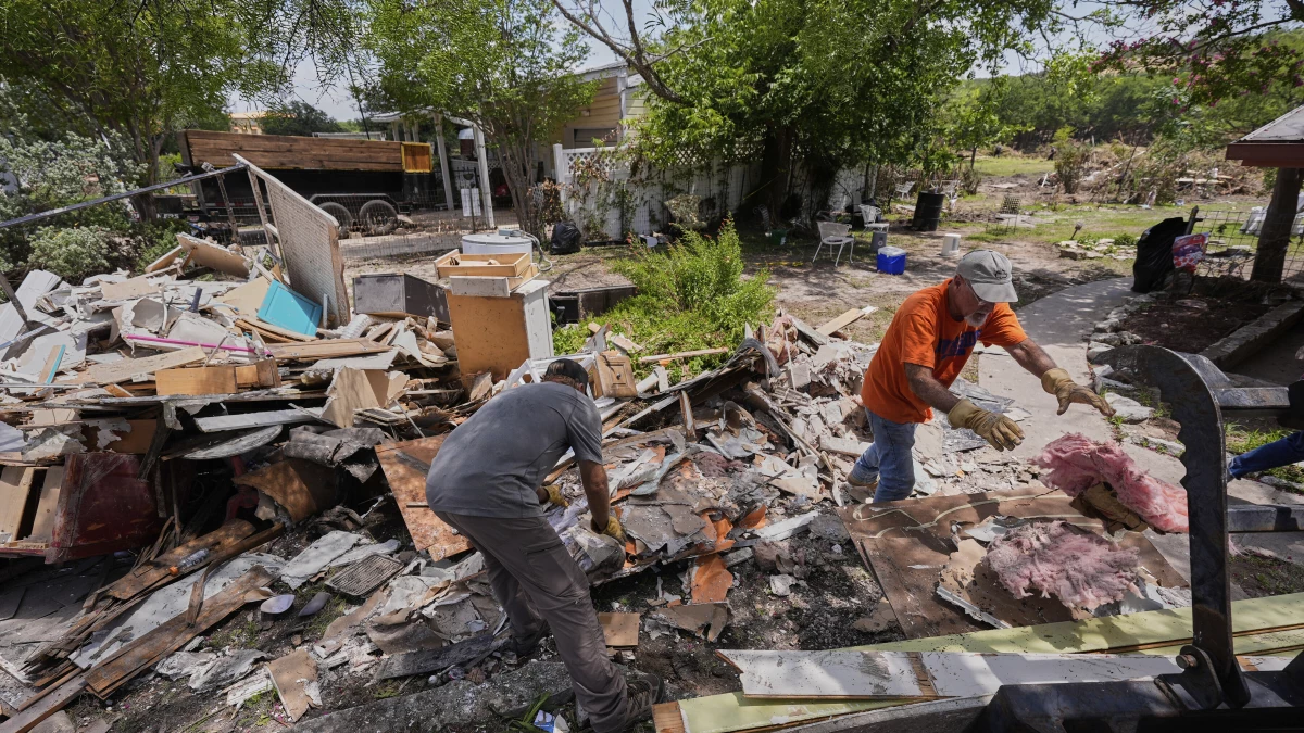 Homeowner Daniel Olivas, right, clears debris from his home that was heavily damaged from flash floods along the Guadalupe River in Kerrville, Texas, on Thursday, July 10, 2025.