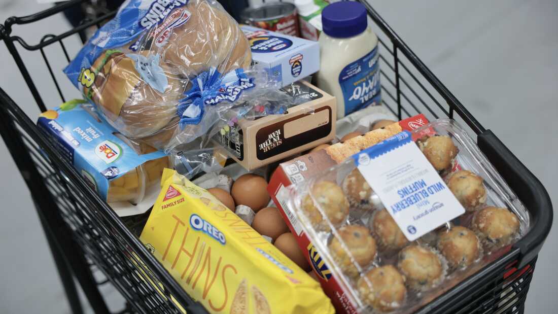 A grocery cart is full of food items.