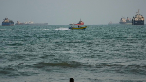 A swimmer remains near the shore as a motorboat passes commercial vessels anchored in the Strait of Hormuz off Bandar Abbas, Iran,on Friday.
