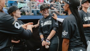 Brittany Apgar (left), Maggie Foxx (center), and Mo'ne Davis (right) of the Los Angeles Queens exchange jokes in the dugout prior to the start of the inaugural game of the Women's Pro Baseball League. Springfield, IL, August 3, 2026.