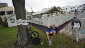 Christopher Reid, 54, a U.S. Army veteran, relaxes in a hammock alongside homemade signs supporting Democratic presidential nominee Vice President Kamala Harris and Florida's Amendments 3 and 4, which would legalize recreational marijuana and enshrine abortion rights in the state, respectively, across from a polling place at the Coliseum in downtown St. Petersburg, Florida on Tuesday.