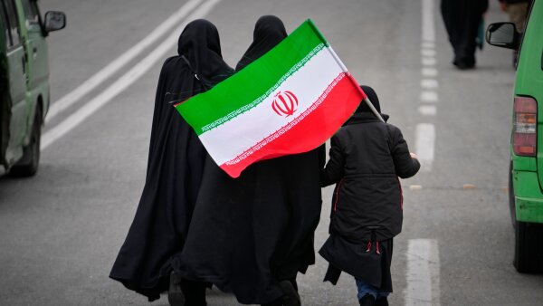 Two women and a child holding an Iranian flag walk toward the Imam Khomeini Grand Mosque to attend Friday prayers in Tehran, Iran.