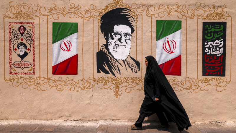 Image 37: A woman walks past a mural depicting Iran's late supreme leader, Ayatollah Ali Khamenei, at Valiasr Square in central Tehran, on Aug. 8. 