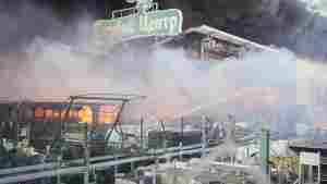 Firefighters try to put out a fire after two guided bombs hit the Epicenter shopping complex in Kharkiv, Ukraine, on Saturday, May 25, 2024. The sign reads 