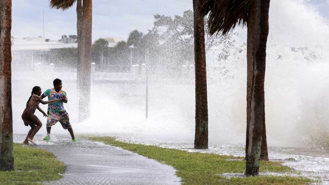 People are splashed by churning surf from Tampa Bay as Hurricane Helene passes offshore on Sept. 26, 2024, in St. Petersburg, Fla.