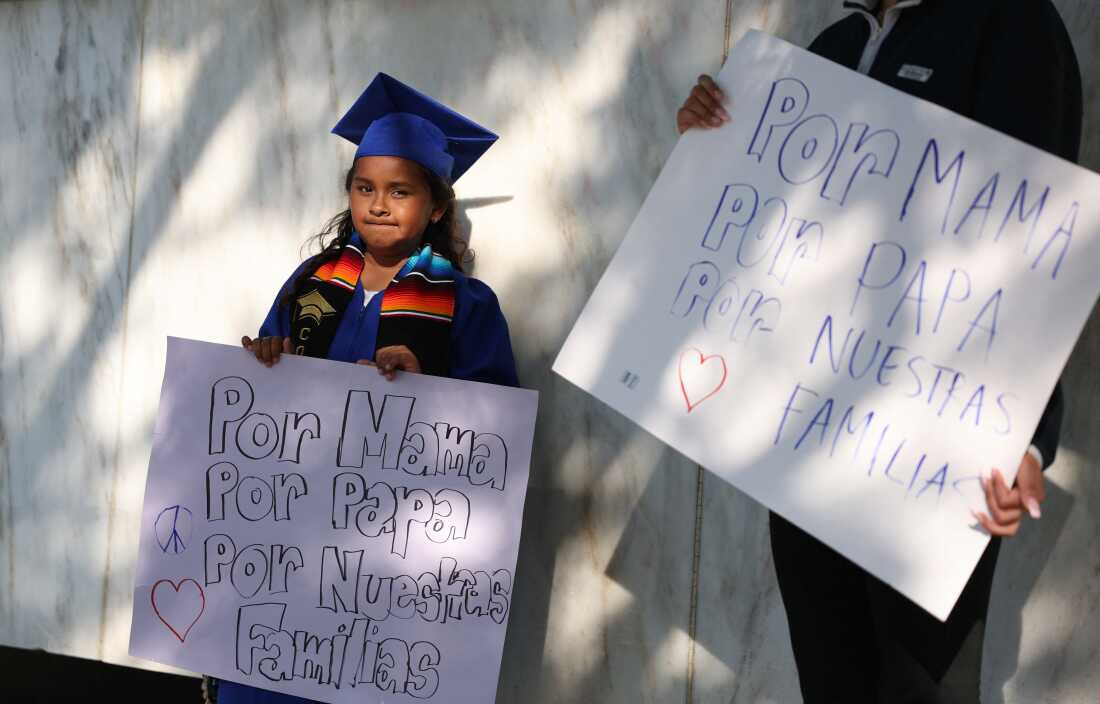A child holds a sign protesting immigration policies.