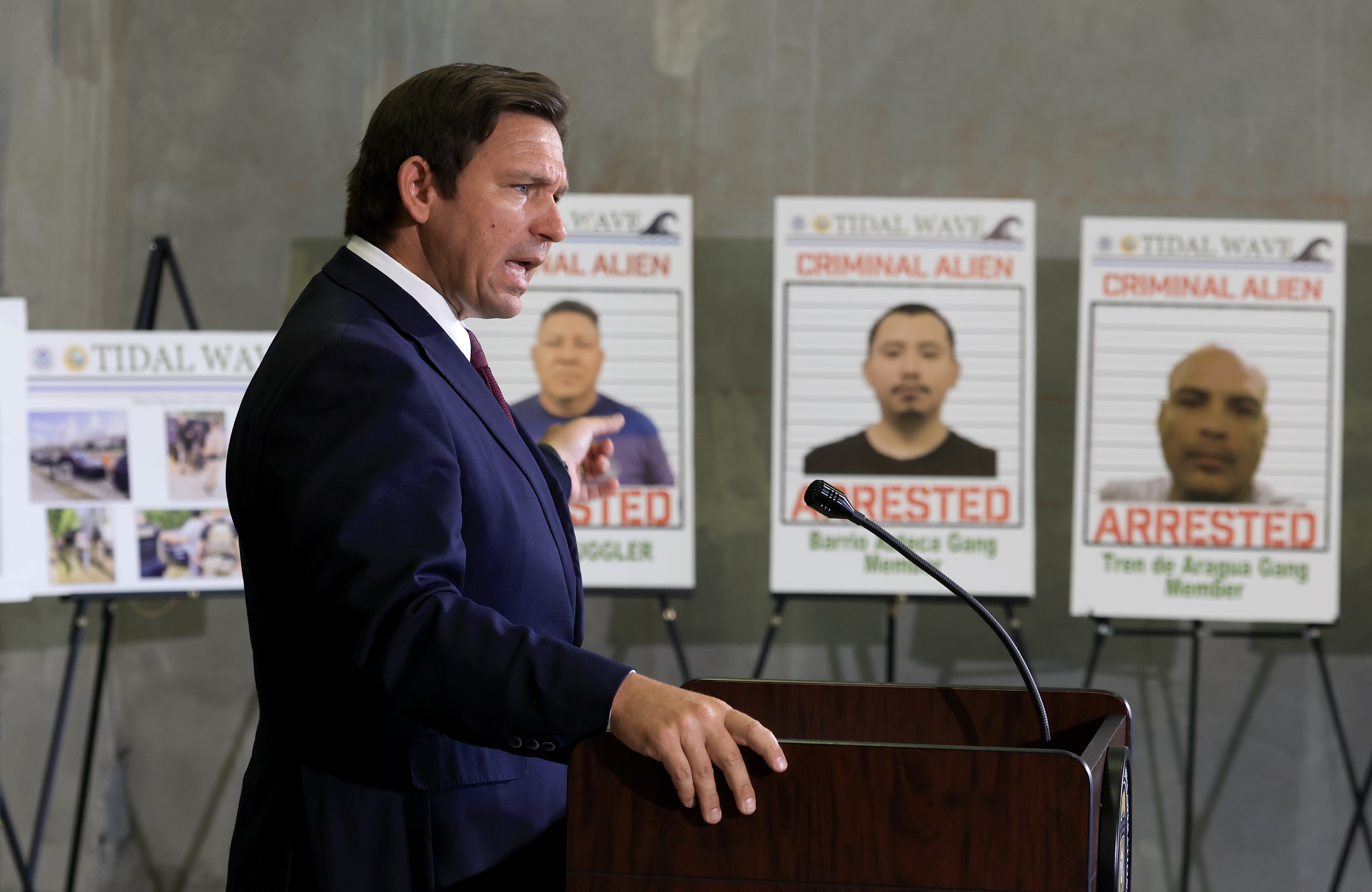 Florida Gov. Ron DeSantis speaks during a press conference, in front of posters of people that law enforcement arrested. DeSantis talked about a multi-agency immigration enforcement effort named Operation Tidal Wave that they say resulted in more than 1,100 arrests in a single week in Florida.