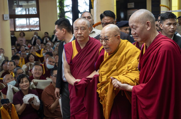 Tibetan spiritual leader the Dalai Lama, in yellow robe, is helped by attendant monks as he arrives to preside over an event during which Tibetan exiles prayed for his longevity, a day before his 90th birthday, in Dharamshala, India, Saturday, July 5, 2025.\