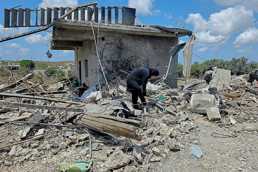 Lübnanlı bir kadın, 26 Temmuz 2026 Pazar günü Lübnan'ın güneyindeki Zawtar al-Gharbiyeh köyünde yıkılan evinin enkazını temizliyor.