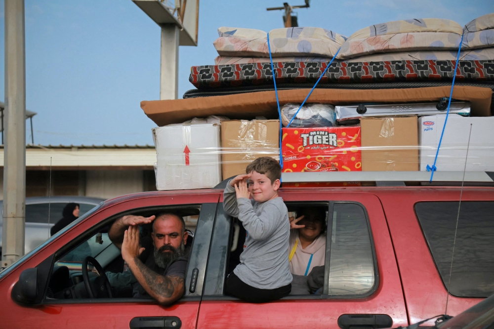 Displaced residents travel through the Qasmieh area as they gesture on the way back to their homes in the southern Lebanon, on Friday, after the start of a 10-day ceasefire deal struck between Lebanon and Israel. Despite the truce, the Israeli military and Hezbollah warned residents not to return to their villages for their own safety. (AFP via Getty Images)