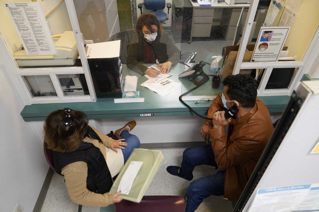 Mohammad Attaie and his wife Deena, newly arrived from Afghanistan, get assistance from medical translator Jahannaz Afshar making a doctor's appointment at the Valley Health Center TB/Refugee Program in San Jose, Calif., on Dec. 9, 2021.