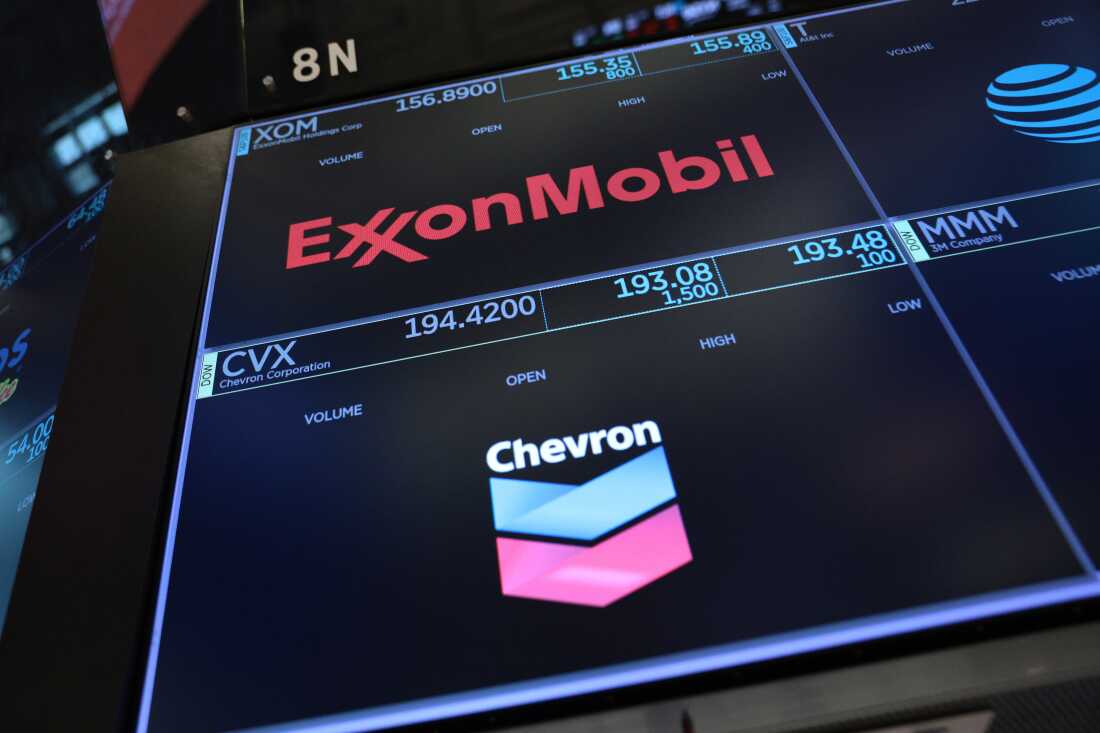 The logos for ExxonMobil and Chevron appear on display screens on the floor of the New York Stock Exchange during morning trading on July 24.