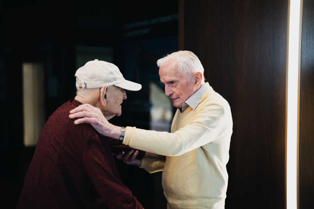 Andrew Roth stands up from his wheelchair to give Jack Moran a hug at the Shoah Foundation USC offices on June 5, 2025. Grace Widyatmadja for NPR
