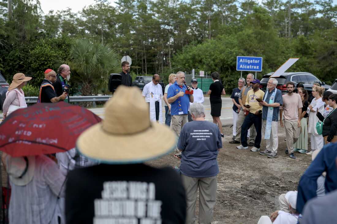 Sunshine Cathedral Bishop Durrell Watkins leads a prayer last Sunday near the entrance to the state-managed immigration detention center dubbed 'Alligator Alcatraz'. Faith leaders were praying for those being held within the facility.