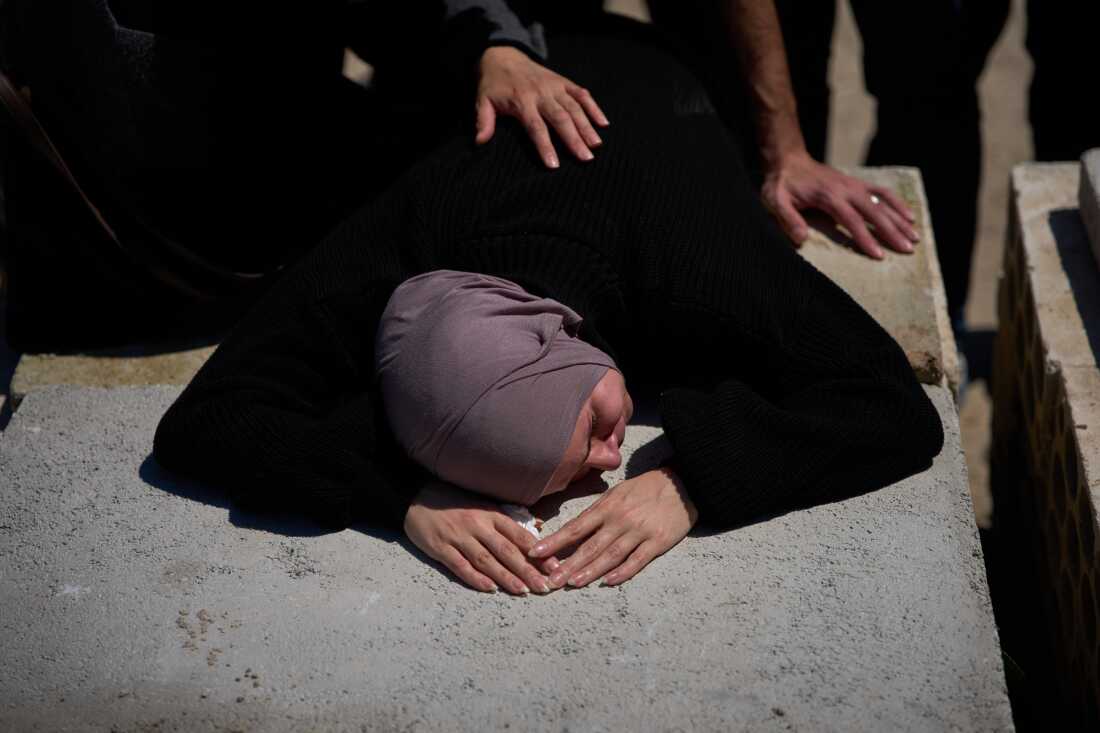 A woman mourns on the grave of her husband during the funeral of 13 state security officers killed the previous day in an Israeli strike in Lebanon's coastal city of Sidon, Saturday, April 11, 2026.