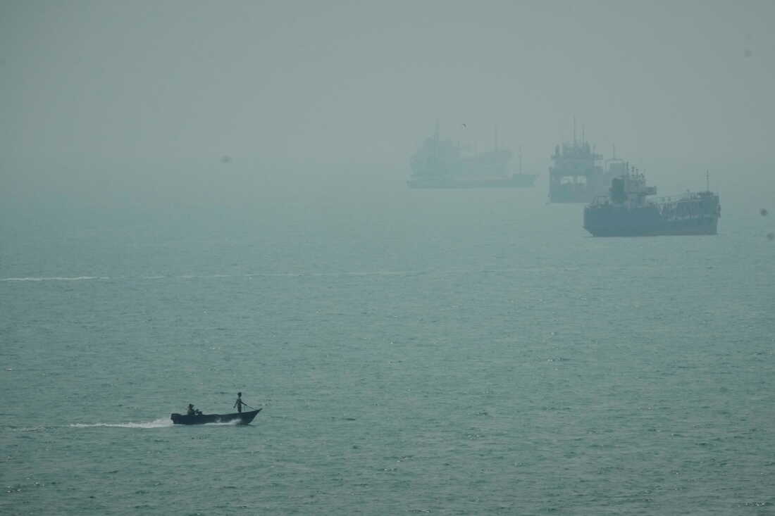 A motorboat travels past commercial vessels anchored amid haze in the Strait of Hormuz off Bandar Abbas, Iran, Monday, Sept. 7, 2026.