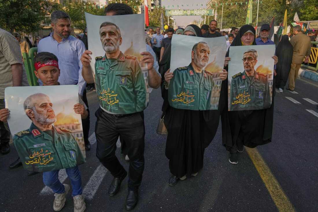 Demonstrators carry posters of top Iranian commanders killed in Friday's Israeli strikes on Tehran, during the Muslim Shiite holiday of Eid al-Ghadir, which commemorates the Prophet Muhammad naming Ali, revered as the first Shiite imam, as his successor, in Tehran, Iran, Saturday, June 14, 2025. 