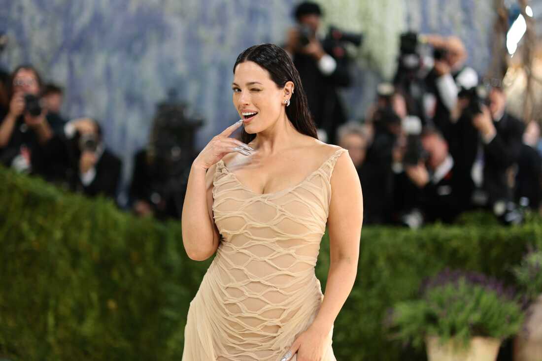 Model Ashley Graham attends the 2026 Met Gala. She is wearing a beige gown and is biting on a silver fingernail.