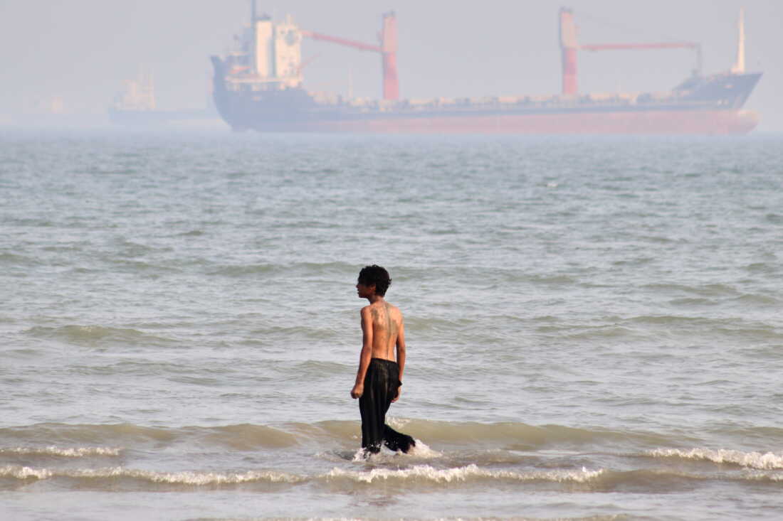 A boy walks on shallow water as commercial vessels are anchored in the Strait of Hormuz off Bandar Abbas, Iran, Monday.