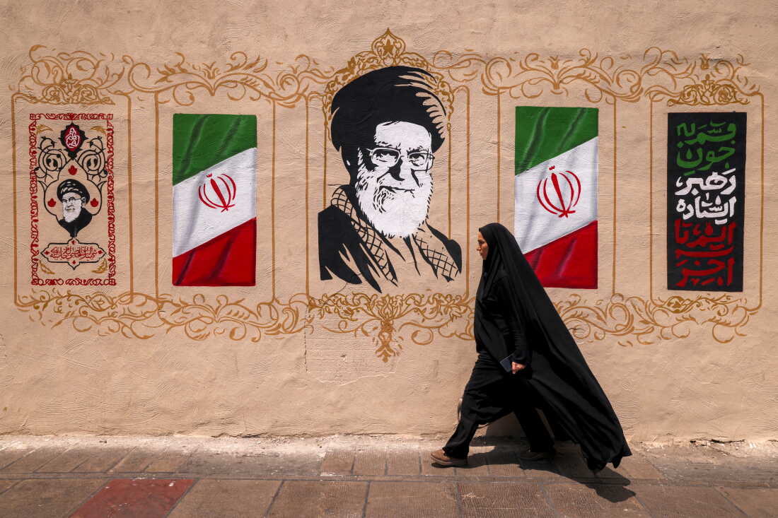 A woman walks past a mural depicting Iran's late supreme leader, Ayatollah Ali Khamenei, at Valiasr Square in central Tehran, on Aug. 8.
