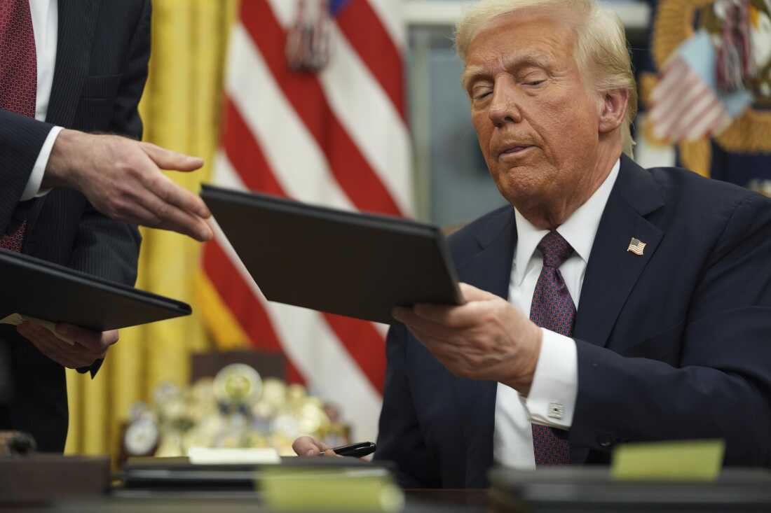President Donald Trump signs executive orders in the Oval Office of the White House on January 20.