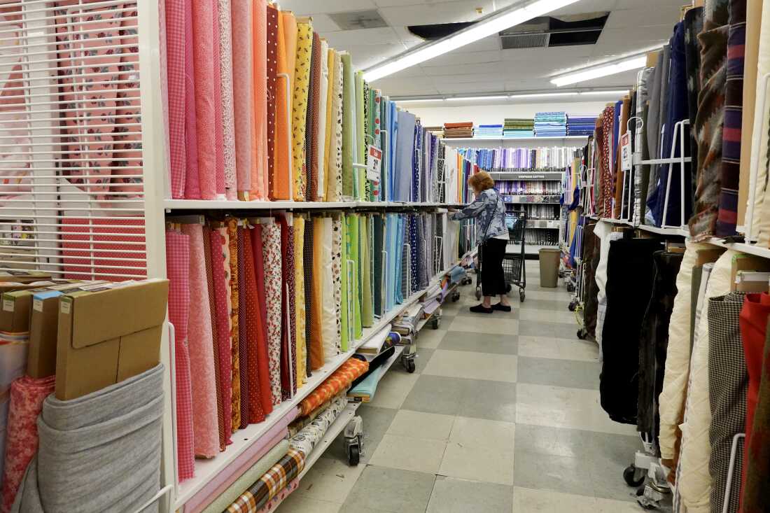 A customer shops in an aisle lined by rolls of fabric at a Joann store in Miami on Feb. 13.
