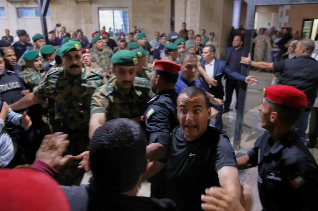 Soldiers and security officers hold back residents outside Prince Ali Military Hospital during King Abdullah II's visit to people wounded when gunmen opened fire during a funeral at a Greek Orthodox church hours earlier, in Karak, Jordan, Friday, Oct. 23, 2026. (AP Photo)