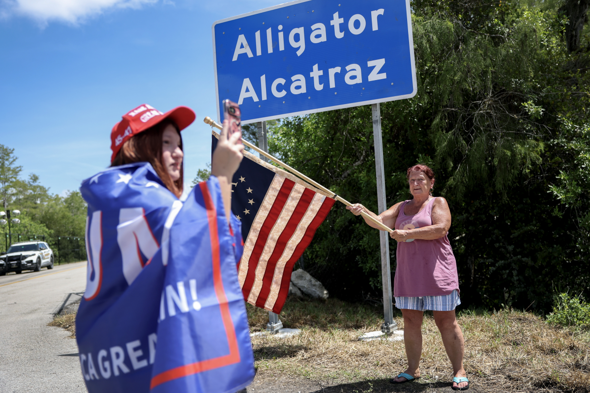 Rena Mourer (left) and Dianna Mourer take pictures at the entrance to 'Alligator Alcatraz' at the Dade-Collier Training and Transition Airport, in Ochopee, Fla., on July 12. Members of Congress were given their first visit to the new state-managed immigration detention facility in the Florida Everglades that officials have named 'Alligator Alcatraz.'