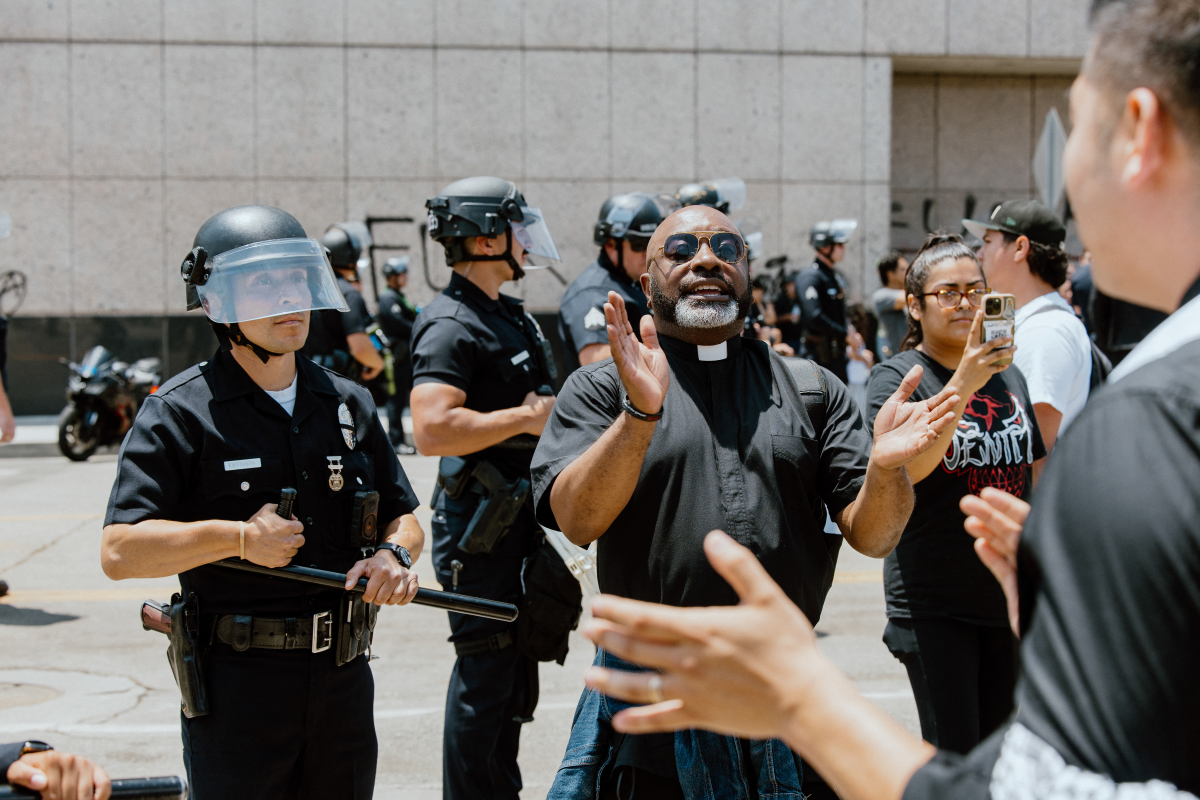 A priest claps as protesters conitnue anti-ICE demonstrations in Los Angeles, California, on June 9, 2025.
