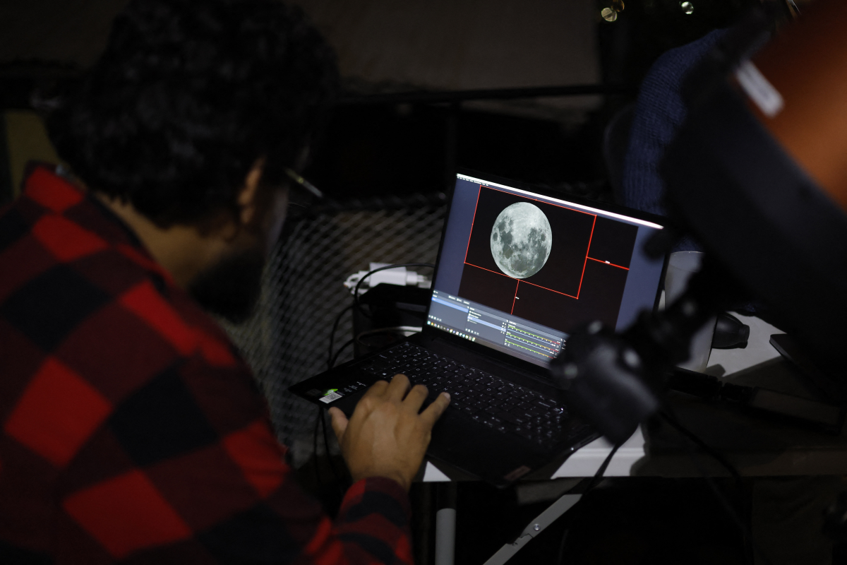 Scientists look at the moon displayed on a screen at the Foster Observatory in Santiago on Friday, prior to the lunar eclipse.
