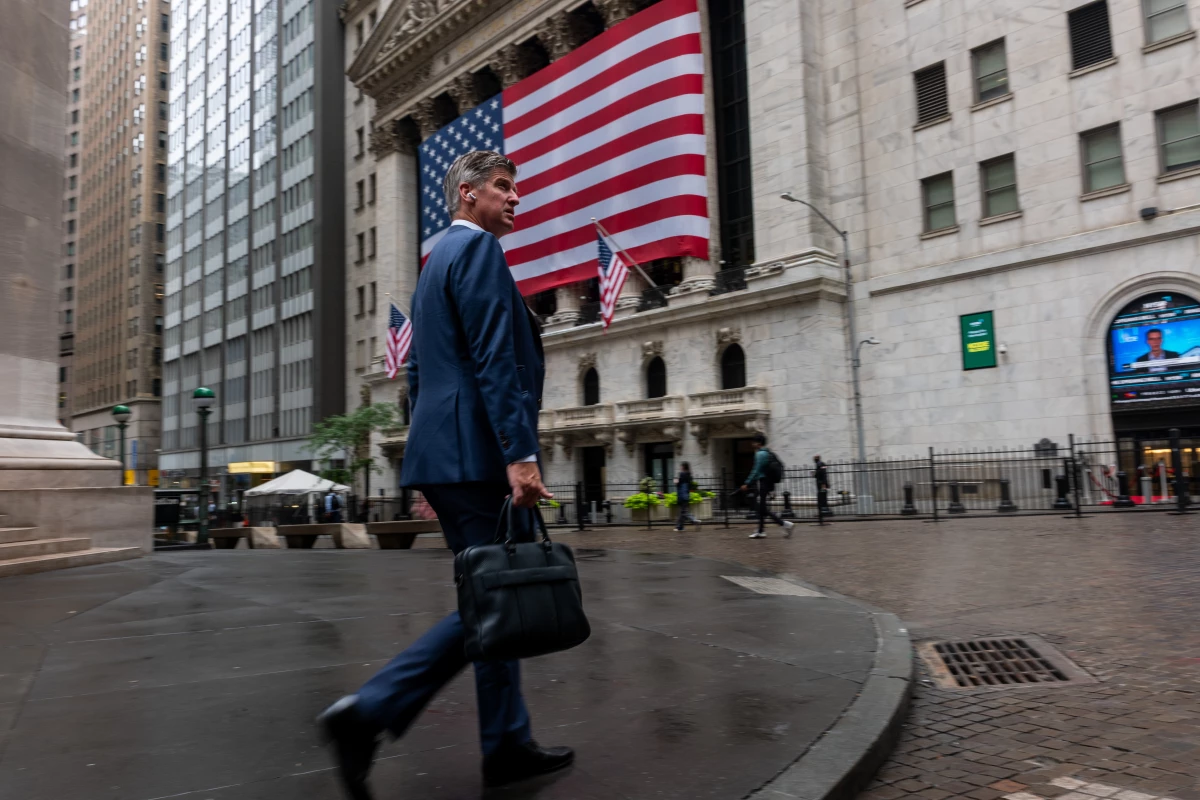 A businessman walks by the New York Stock Exchange in New York City. As more than 100 big companies reported earnings this week, the S&P 500 and Nasdaq hit a series of record highs.