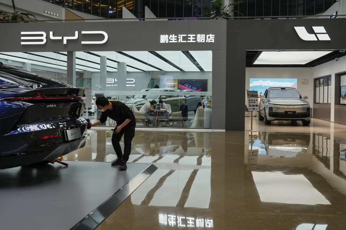 A worker wipes a Rising F7 car model at a floor section selling various Chinese-made electric car brands inside a shopping mall in Beijing, Tuesday, April 4, 2023. (AP Photo/Andy Wong)