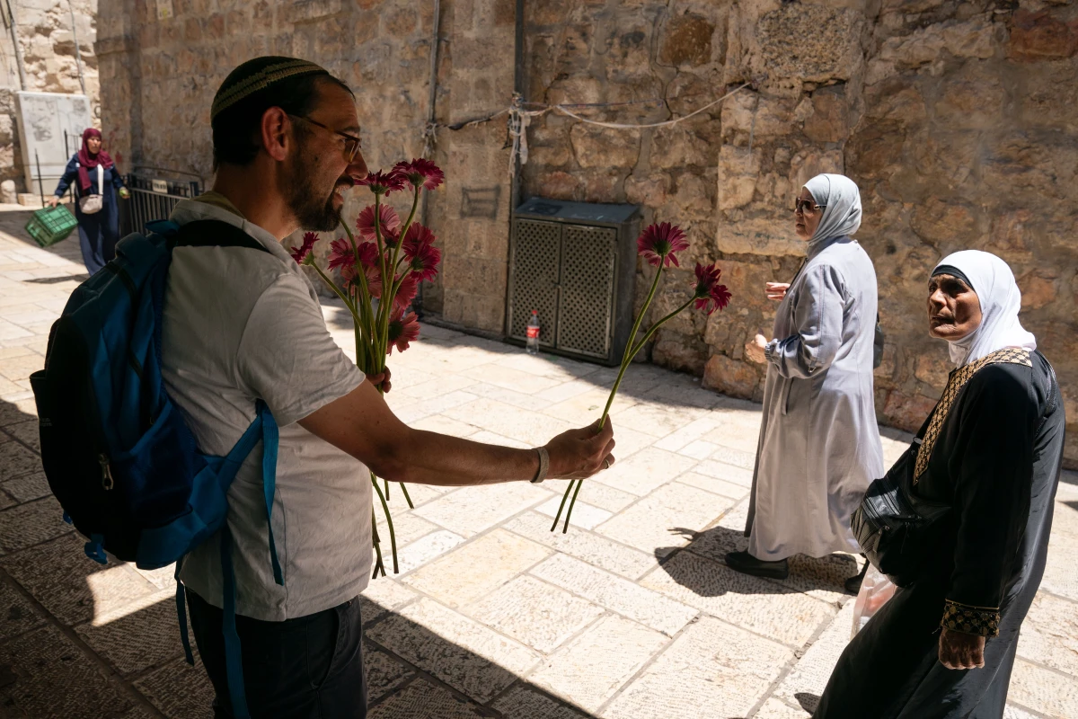 A member of Tag Meir, an Israeli group working against hate crime and racism, hands out flowers to residents of the Old City before the march begins.