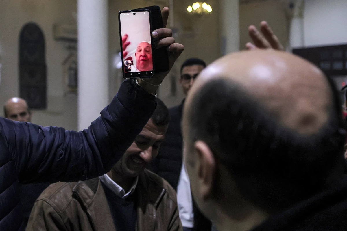A man holds up a phone for the Rev. Gabriel Romanelli, parish priest of Gaza City's Roman Catholic Church of the Holy Family, to have a video call with Pope Francis as the pope blesses the congregation during Christmas Eve Mass, Dec. 24, 2024.