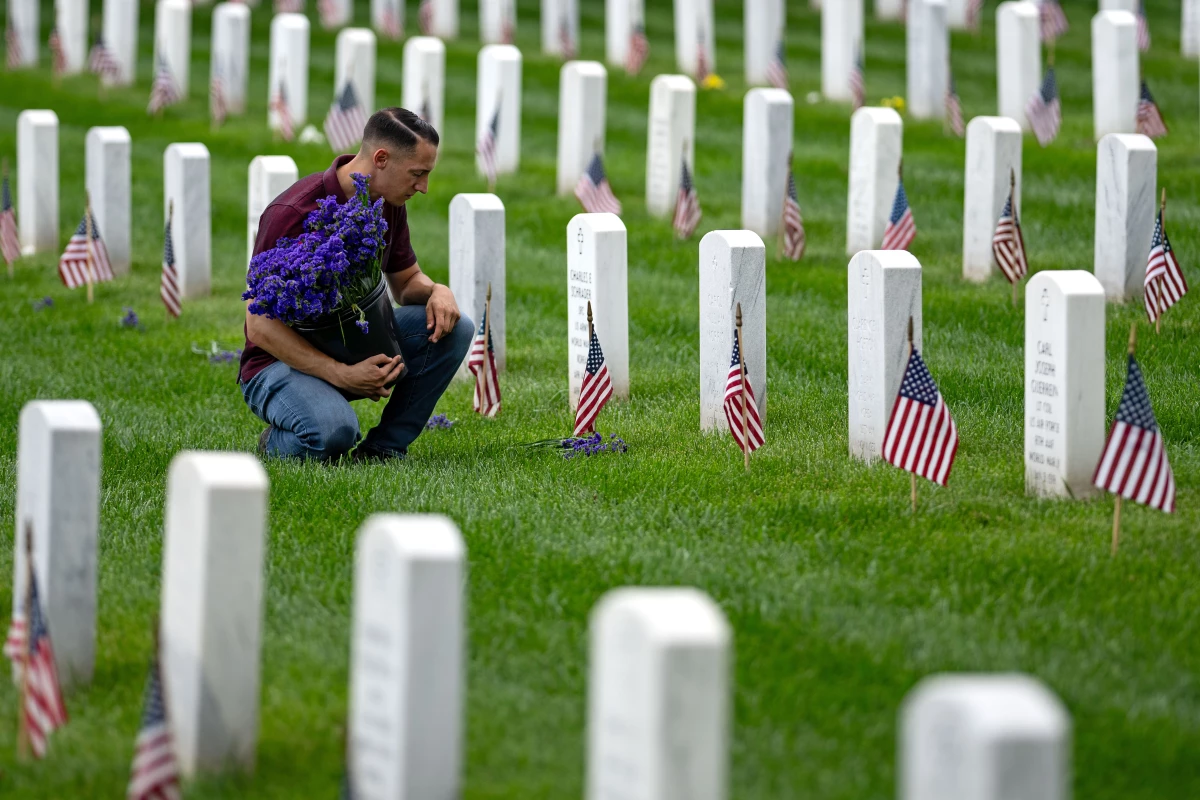 A man places flowers in front of headstones in Section 60, which mark the final resting place of service men and women at Arlington National Cemetery on May 27 in Arlington, Va.