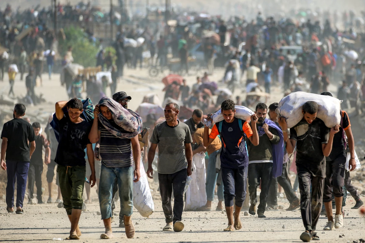 People walk with humanitarian aid packages that they received from a distribution center run by the U.S. and Israeli-backed Gaza Humanitarian Foundation, at the so-called 'Netzarim corridor,' in Nuseirat in the central Gaza Strip, on Sept. 30, 2025.