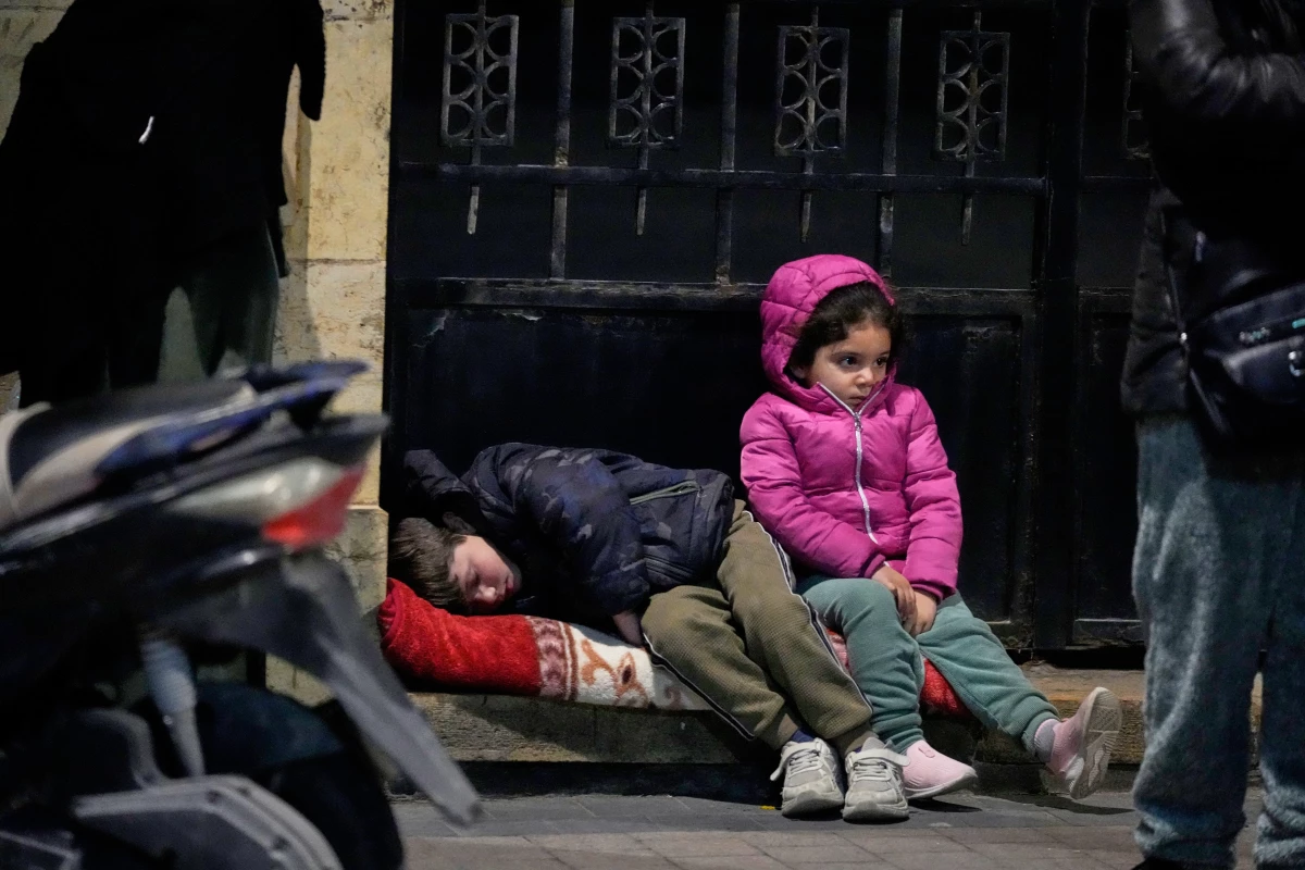 March 2: Children sit on a sidewalk as displaced families fleeing Israeli strikes in southern Lebanon arrive in the southern port city of Sidon.