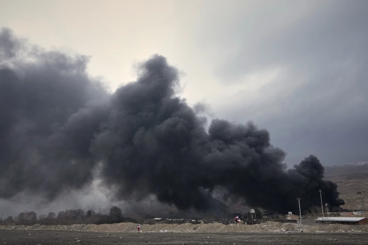 A thick plume of smoke rises from an oil storage facility hit by a U.S.-Israeli strike late Saturday in Tehran, Iran, Sunday, March 8, 2026.